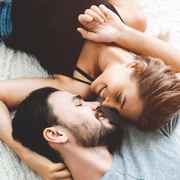 younger couple in bed, looking at each other lovingly